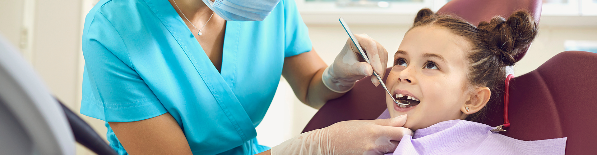 Dentist using dental tool in child's mouth.